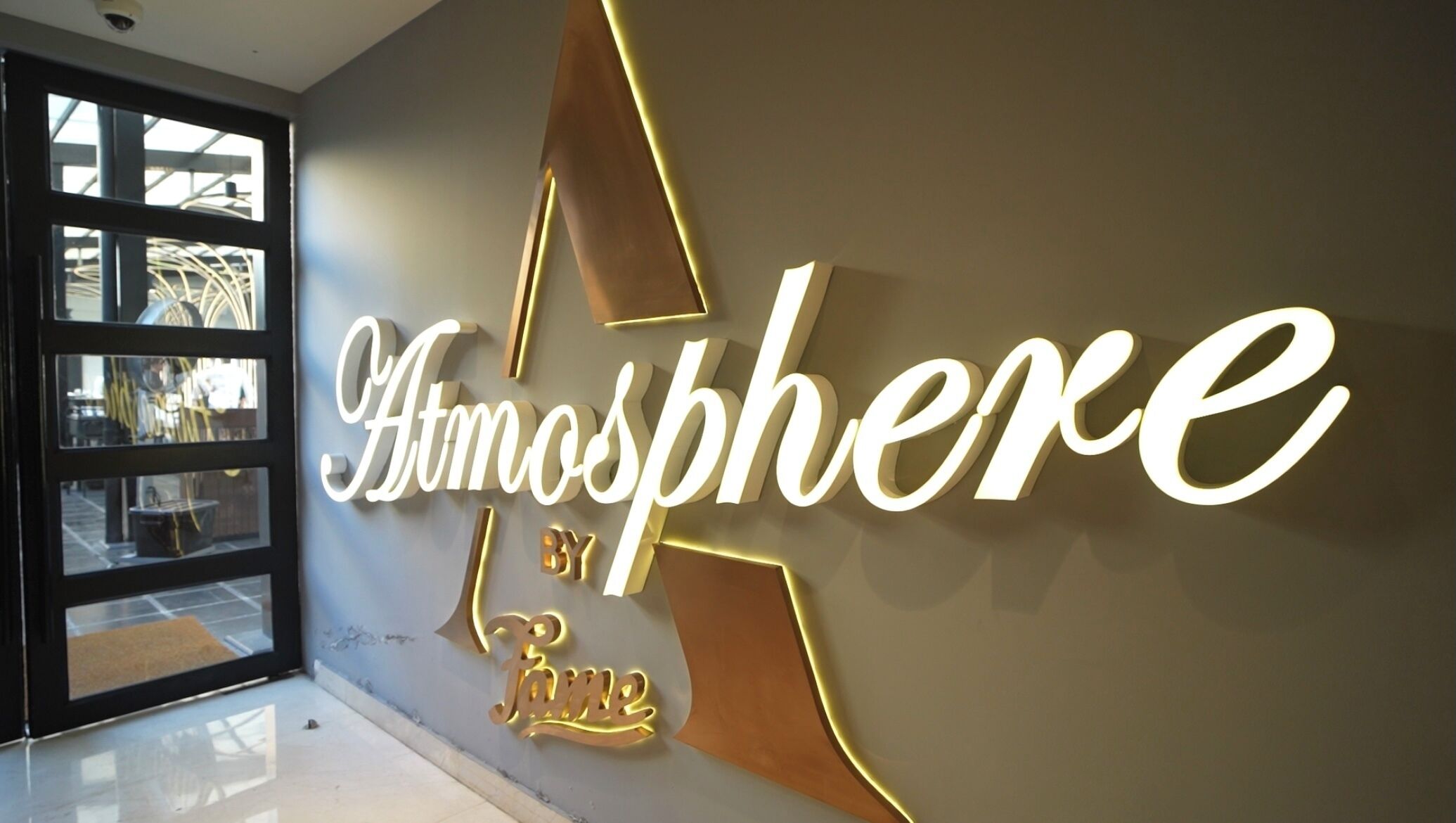 A wall with illuminated signage reading "Atmosphere by Rose."