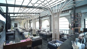A modern restaurant with a high ceiling, unique lighting, and a variety of seating arrangements. - Planet Hollywood (Thane)