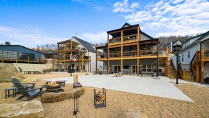 A spacious outdoor area with a fire pit, seating, and a multi-level building with balconies. - Private Basketball Court/Hot Tub-Community Pools (Branson)