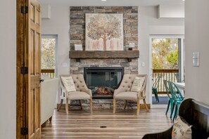 Cozy living room with a fireplace, armchairs, and large windows.