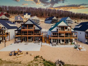 Zona residencial con varias casas de dos pisos con balcones, una playa arenosa y un fondo boscoso.