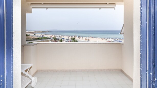 Een balkon met uitzicht op een strand en verre bergen.