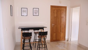 Un coin repas avec une table noire et quatre chaises, une porte en bois et deux tableaux encadrés au mur.