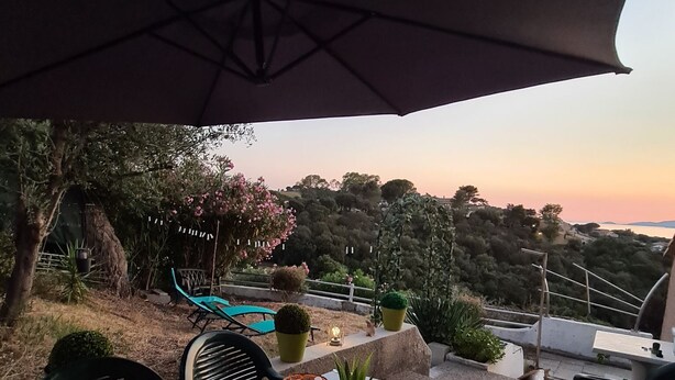An outdoor patio with a table and chairs, a decorative lantern, and a view of the landscape.