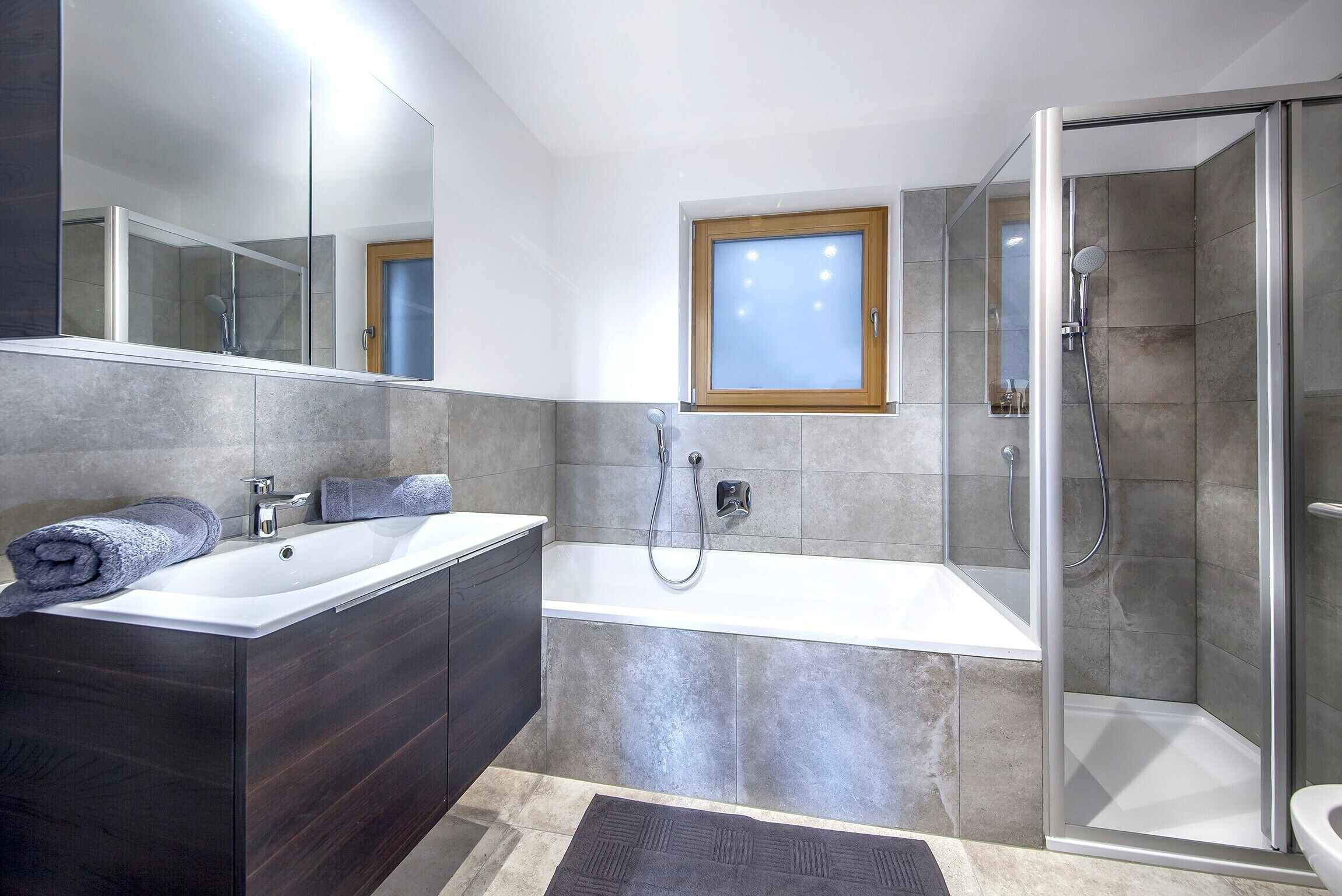 Une salle de bain moderne équipée d’une baignoire, d’une douche et d’un meuble-lavabo avec un miroir.
