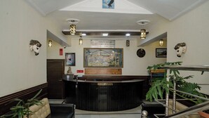 A reception area with a black reception desk, a framed map, and a staircase with a metal railing. - Hotel Falcon Crest (Kandaghat)