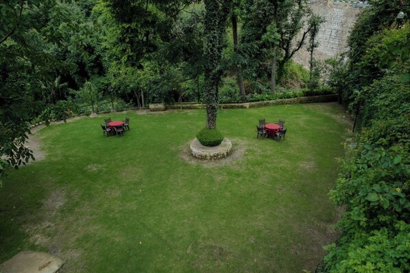 A circular garden with a central tree and three tables with red coverings. - Hotel Falcon Crest (Kandaghat)