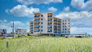 A multi-story residential building with balconies, located near a grassy area with a clear sky. - Oceanview Oasis by Bayley Vacation Rentals (Old Orchard Beach)