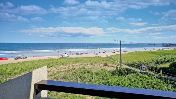 A beach with people, umbrellas, and a pier in the background. - Oceanview Oasis by Bayley Vacation Rentals (Old Orchard Beach)