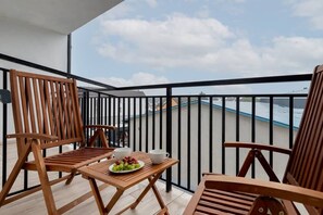 A balcony with wooden furniture, a table with a plate of fruit, and a view of buildings in the background. - Comfortable Apartment with Balcony | 3 minutes to the Beach (Dziwnówek)