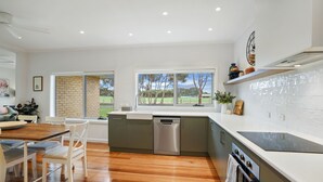 Cozinha moderna com lava-louças, forno embutido e amplas janelas com vista para o exterior.