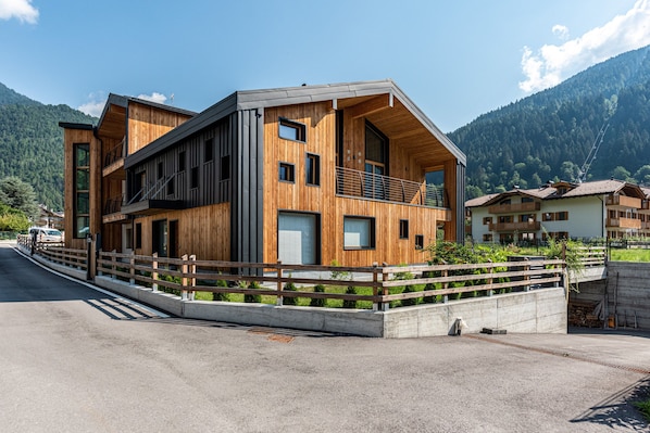 Un bâtiment moderne à deux étages, doté d’une façade en bois, de grandes fenêtres et d’un balcon.