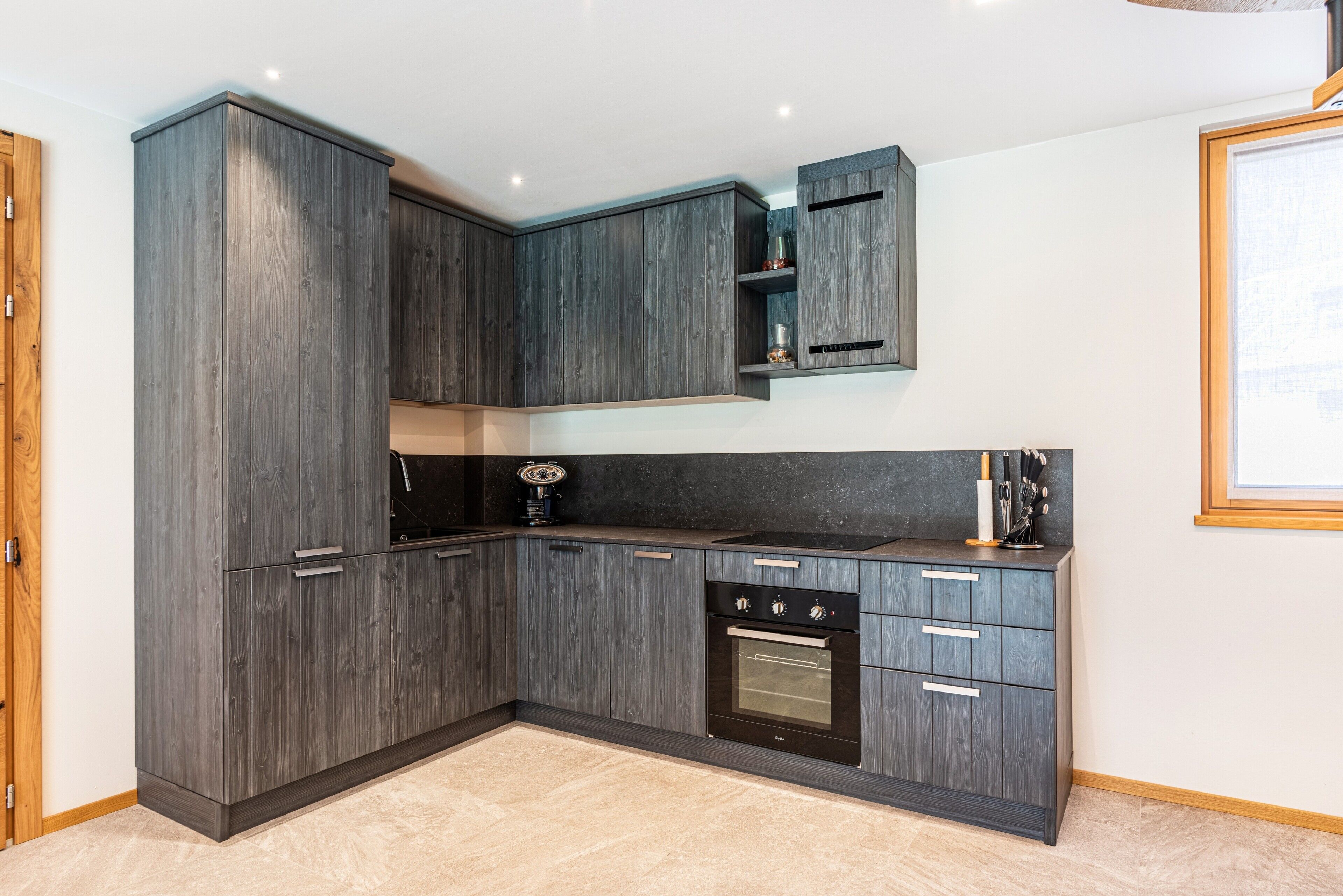 A modern kitchen with dark wood cabinetry, a built-in oven, and a countertop with a coffee machine.