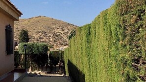 A narrow alleyway with a building on the left and a neatly trimmed hedge on the right. - Pet-Friendly Villa Casa Cuesta with Pool & Garden (Bolnuevo)