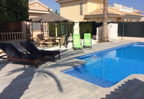 A swimming pool with lounge chairs, a pergola, and a stone table. - Pet-Friendly Villa Casa Cuesta with Pool & Garden (Bolnuevo)