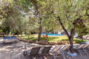 Un espace aménagé au bord de la piscine, avec des chaises longues, un hamac et une aire de jeux.
