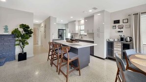 Una cocina moderna con una isla central, taburetes de bar y una mesa de comedor con sillas.