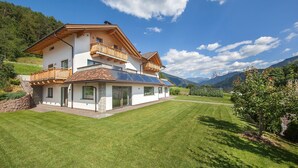 Une maison à deux étages dotée d’un balcon, de panneaux solaires et d’une pelouse bien entretenue.