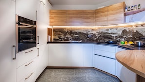 Une cuisine moderne avec des meubles blancs, un plan de travail noir et un pare-feu en marbre.