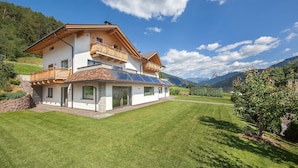 Une maison à deux étages dotée d’un balcon, de panneaux solaires et d’une pelouse bien entretenue.