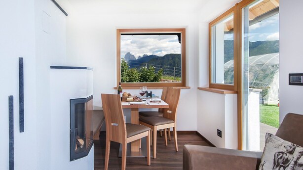 Una habitación moderna con una mesa de comedor, sillas, un sofá y un amplio ventanal con vistas a la montaña.