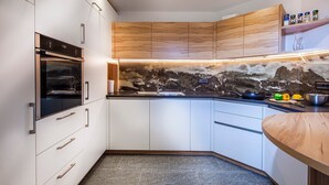 Una cocina moderna con armarios blancos, encimera negra y salpicadero de mármol.