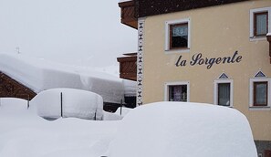 A building with the name 'la Sorgente' partially visible, surrounded by snow-covered objects.