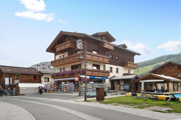 A multi-story wooden building with balconies, a covered outdoor seating area, and a pool.