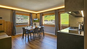 Een modern interieur met een eethoek, keuken en grote ramen met uitzicht op een bergachtig landschap.