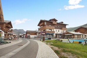 A mountain resort with wooden buildings, a paved road, and a pool area.