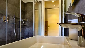 Un baño moderno con cabina de ducha de vidrio, un lavabo blanco y un grifo cromado.