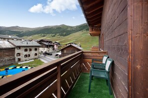 A balcony with a view of a village, wooden buildings, and a mountain backdrop.