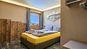 Un dormitorio con cama, paneles de madera, ventana con vistas y un aplique de pared.