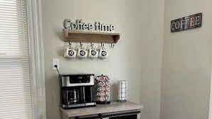 Un coin cuisine équipé d’un espace pour préparer le café, comprenant une machine à café, des tasses et une poubelle.