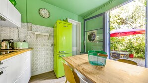 A kitchen with a green refrigerator, wooden countertop, and a window with an umbrella.