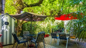 An outdoor patio with stone flooring, metal chairs, a table, and a large umbrella.