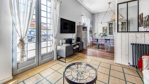 A living room with a TV, a coffee table, and a dining area with chairs.