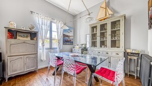 A dining area with a glass table and chairs, a cabinet with glass doors, and a window with curtains.