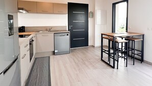 Una cocina moderna con lavavajillas, una puerta negra y un comedor con mesa y sillas.