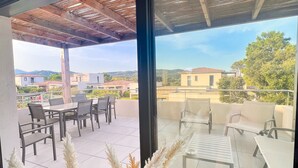 Un patio moderno al aire libre con una pérgola, mobiliario y vistas del vecindario.