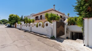 A residential building with a gated entrance, a driveway, and a clear sky.