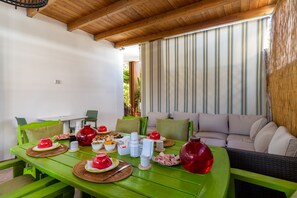 A dining area with a table set for a meal, a sofa, and a view of the outdoors.