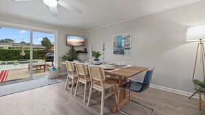 Een eethoek met een houten tafel, rieten stoelen en een plafondventilator.