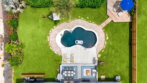 Vista aérea de un patio trasero con piscina, zona de barbacoa y terraza amueblada.