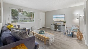 Una sala de estar con un sofá, una mesa de centro y un televisor montado en la pared.