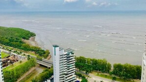 A high-rise building with a view of a river and greenery.
