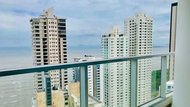 A high-rise building with multiple floors, large windows, and a view of the sea.