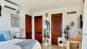 A bedroom with a bed, bedside table, lamp, and a wooden door.