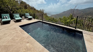 A swimming pool with two lounge chairs and a view of a mountainous landscape.