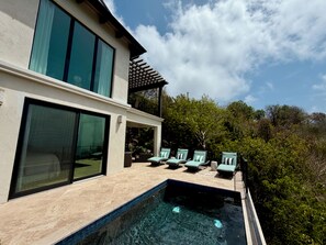 Una casa moderna con piscina, ventanas amplias y zona de estar al aire libre.